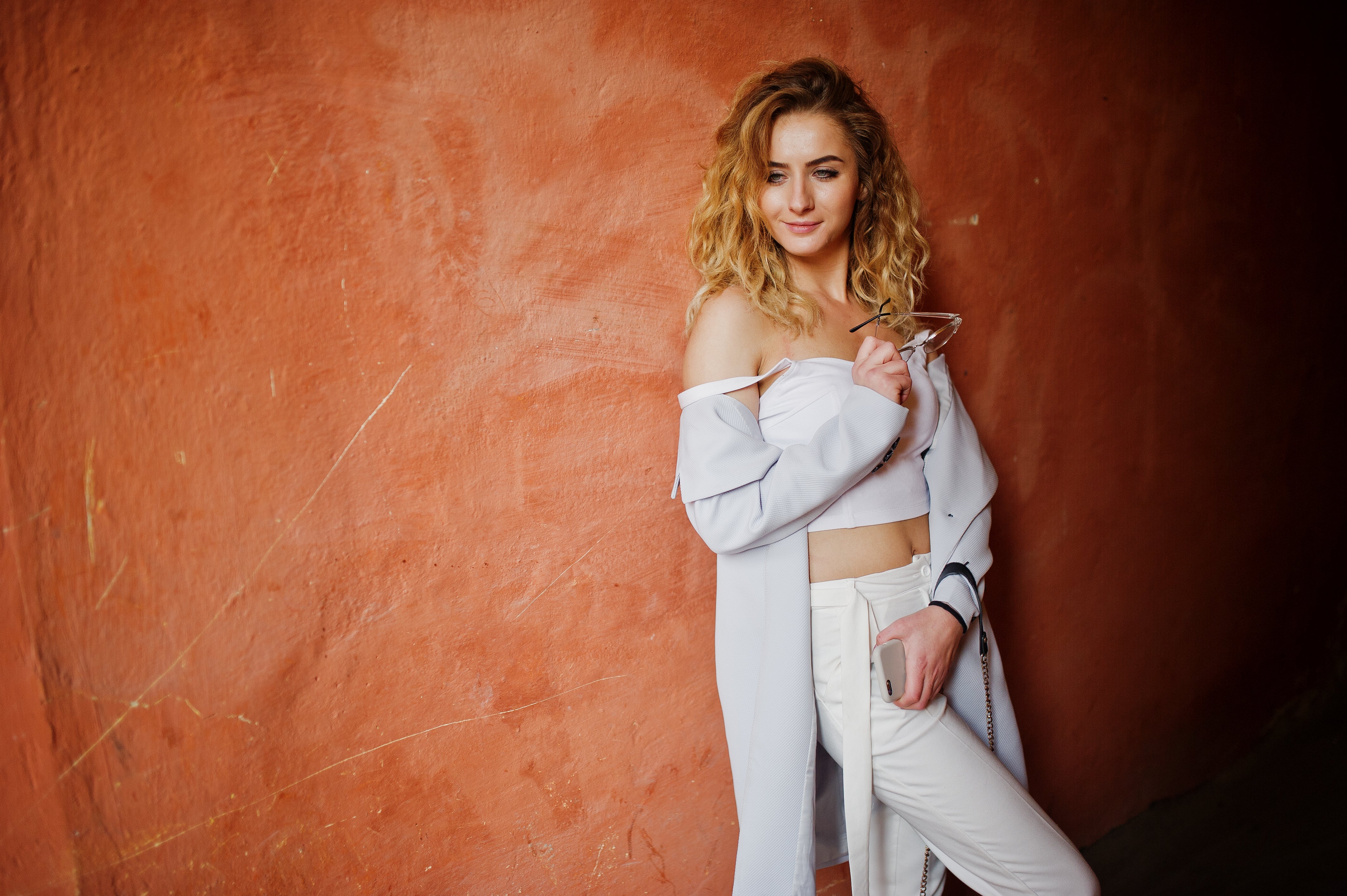 files/stylish-curly-blonde-model-girl-wear-white-posing-against-orange-wall.jpg